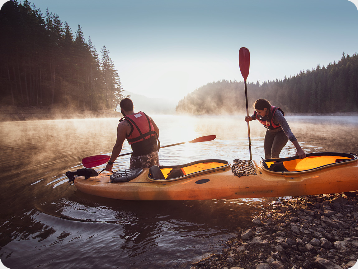 Two people prepare to adventure with kayak in mountain lake.